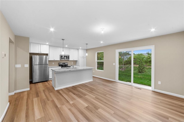 kitchen featuring light wood-style floors, baseboards, appliances with stainless steel finishes, and white cabinets