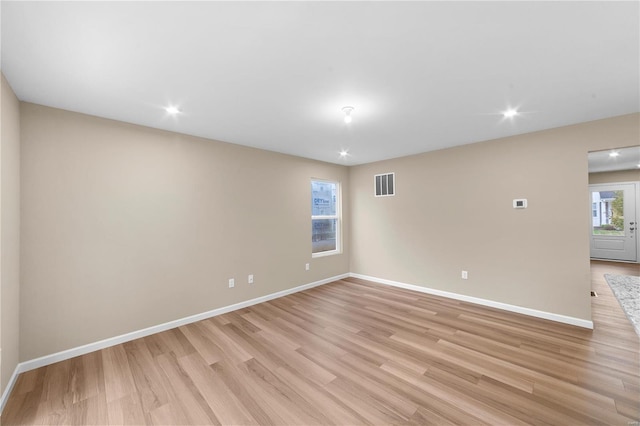 unfurnished room featuring visible vents, light wood finished floors, and baseboards