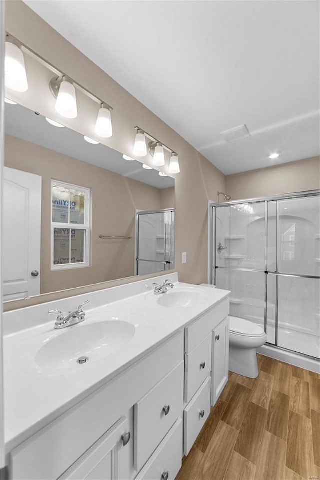 full bath with a sink, a stall shower, toilet, and double vanity