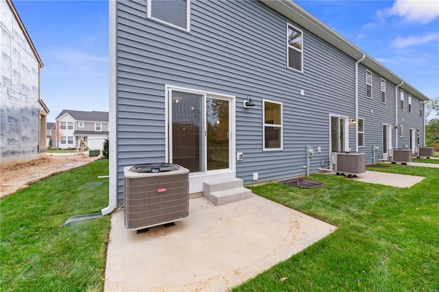 rear view of property featuring central AC unit, a yard, and a patio area
