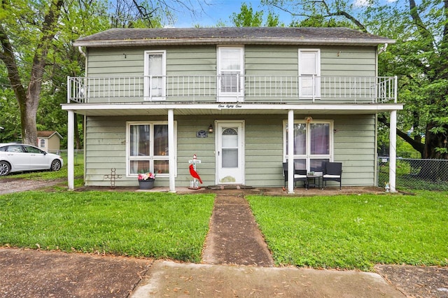 view of front of home featuring a porch, fence, a balcony, and a front yard