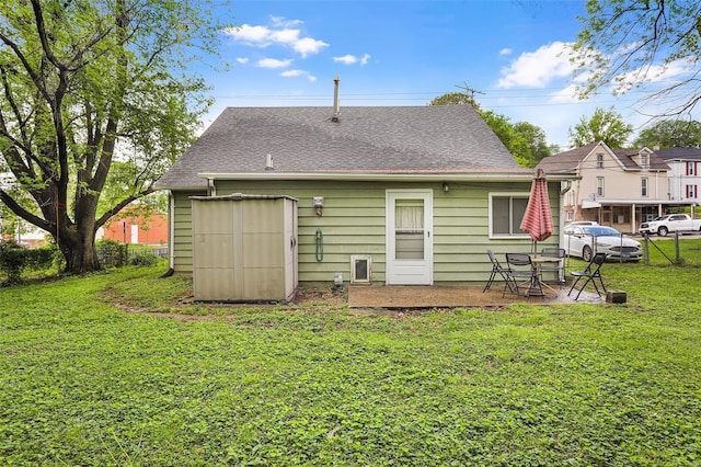 rear view of house featuring a yard, a patio, fence, and a shingled roof