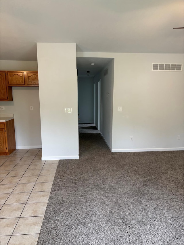 spare room featuring baseboards, light colored carpet, and visible vents