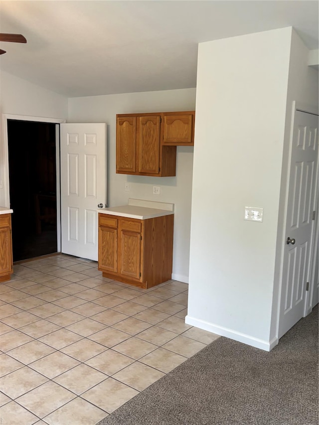kitchen with light countertops, ceiling fan, brown cabinets, and light tile patterned flooring