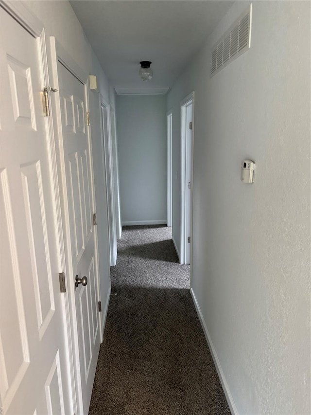 corridor with baseboards, dark colored carpet, and visible vents
