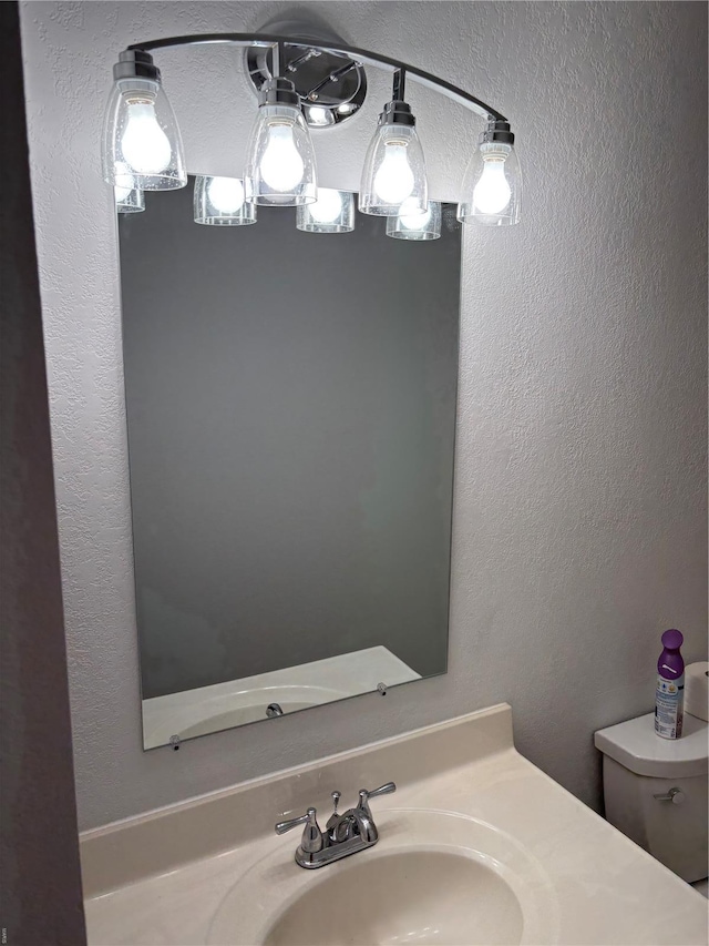 bathroom featuring toilet, a textured wall, and vanity
