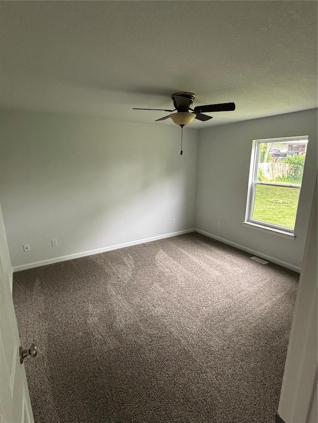 carpeted spare room featuring baseboards, a ceiling fan, and visible vents