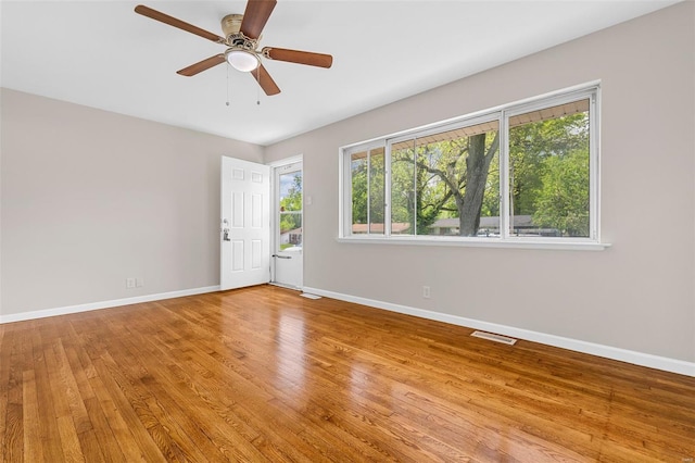 spare room featuring baseboards, a ceiling fan, light wood finished floors, and visible vents