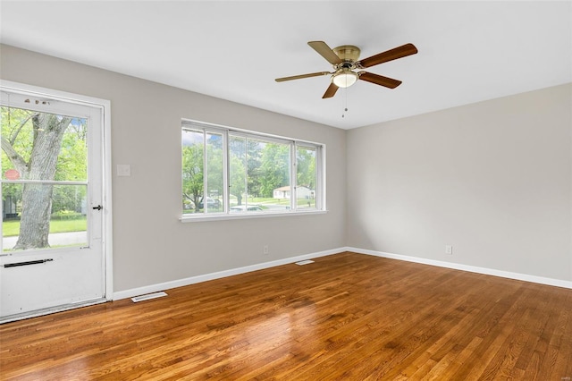 interior space with a healthy amount of sunlight, baseboards, wood finished floors, and visible vents