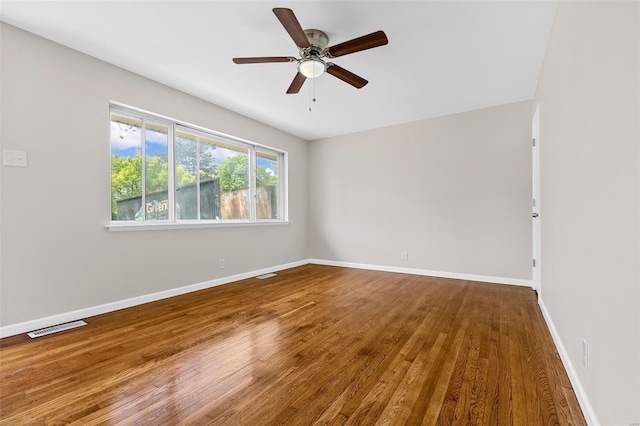 empty room featuring visible vents, baseboards, ceiling fan, and wood finished floors