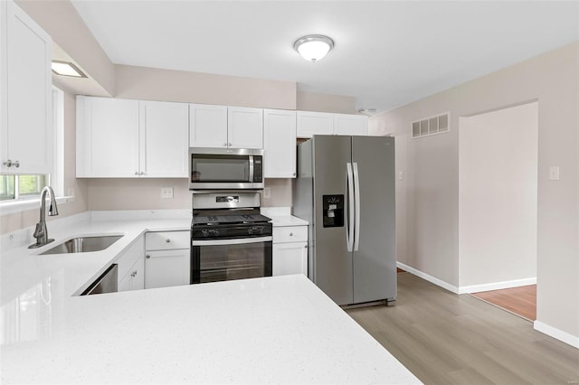 kitchen with visible vents, appliances with stainless steel finishes, light wood-type flooring, a sink, and light countertops