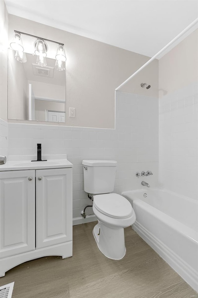 full bathroom featuring vanity, toilet, tile walls, bathing tub / shower combination, and wood finished floors