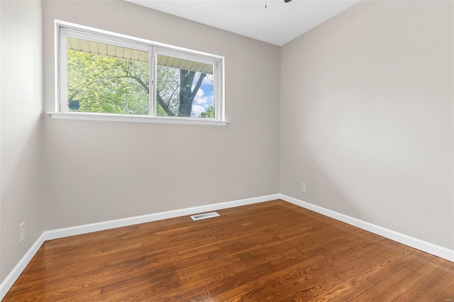 empty room with a ceiling fan, baseboards, visible vents, and wood finished floors