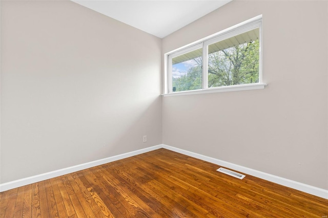 unfurnished room with visible vents, baseboards, and wood finished floors