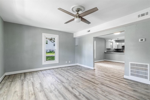 unfurnished living room featuring baseboards, ceiling fan, visible vents, and wood finished floors