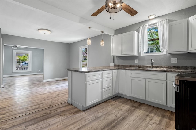kitchen with a sink, a ceiling fan, a peninsula, and a healthy amount of sunlight
