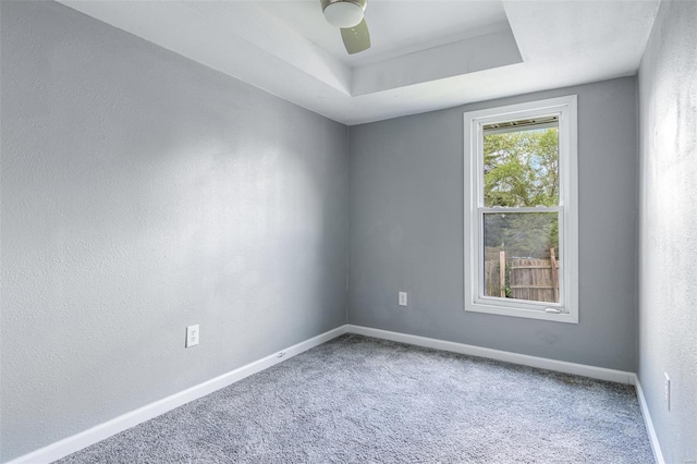 unfurnished room featuring carpet floors, baseboards, ceiling fan, and a tray ceiling