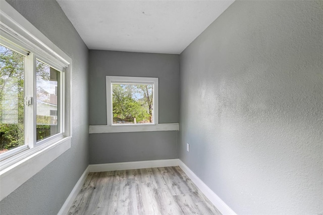 spare room with baseboards, a healthy amount of sunlight, and wood finished floors