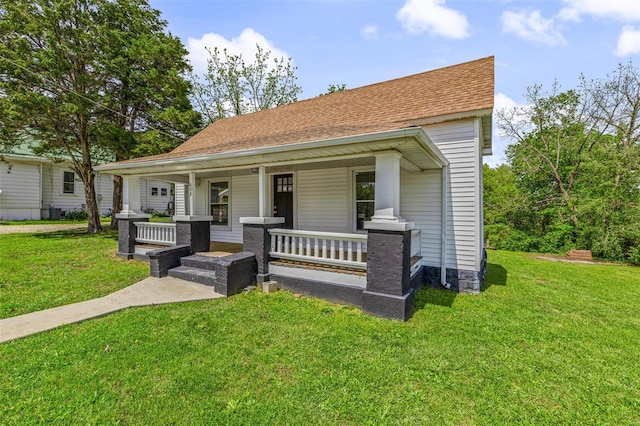 bungalow-style house with covered porch, a shingled roof, and a front lawn