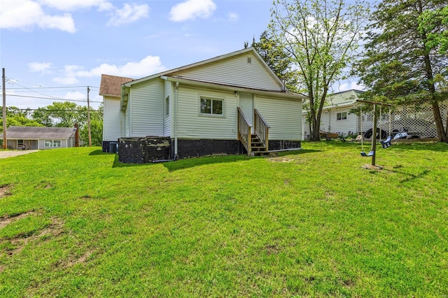 back of house with entry steps, central AC unit, and a yard