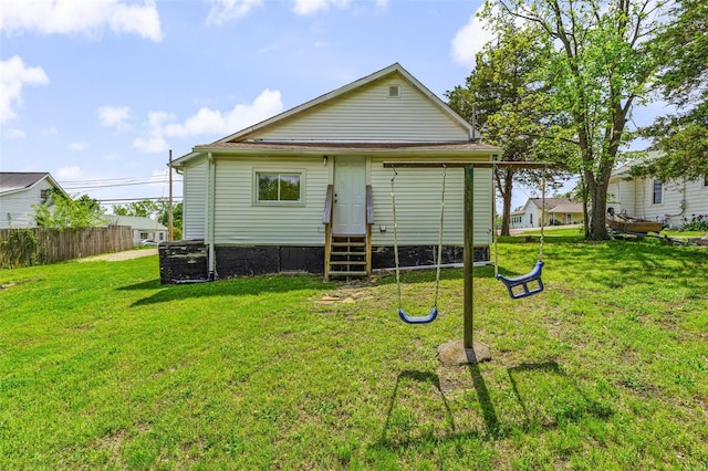 rear view of house featuring entry steps, fence, and a yard