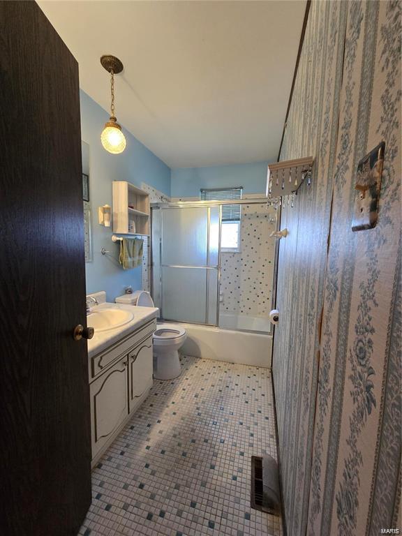 full bath with toilet, bath / shower combo with glass door, and vanity
