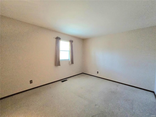 unfurnished room with visible vents, baseboards, and light colored carpet