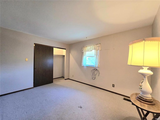 unfurnished bedroom featuring baseboards, light carpet, and a closet