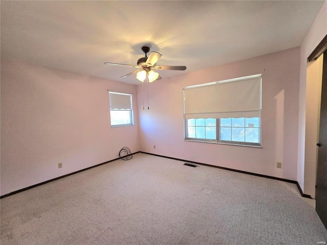 carpeted empty room with visible vents, baseboards, and ceiling fan