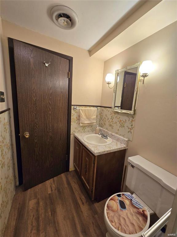 bathroom with vanity, a wainscoted wall, toilet, and wood finished floors