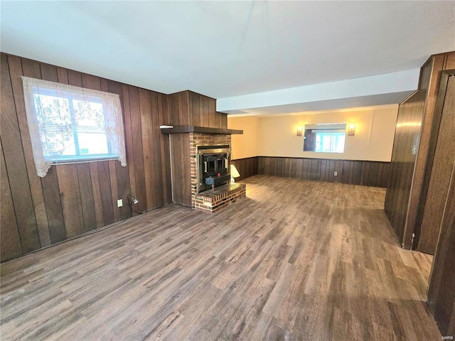 unfurnished living room with wooden walls, wainscoting, wood finished floors, and a fireplace