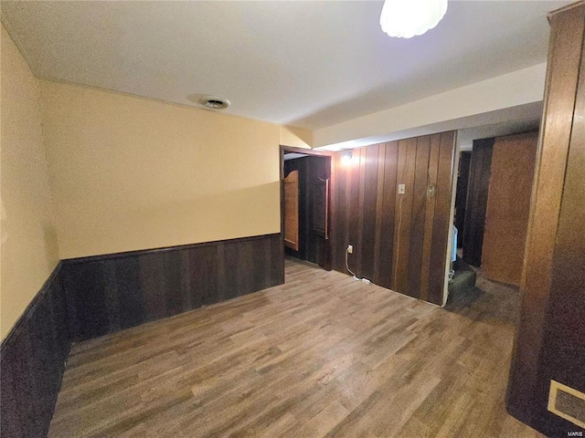 spare room featuring visible vents, wood walls, wainscoting, and wood finished floors