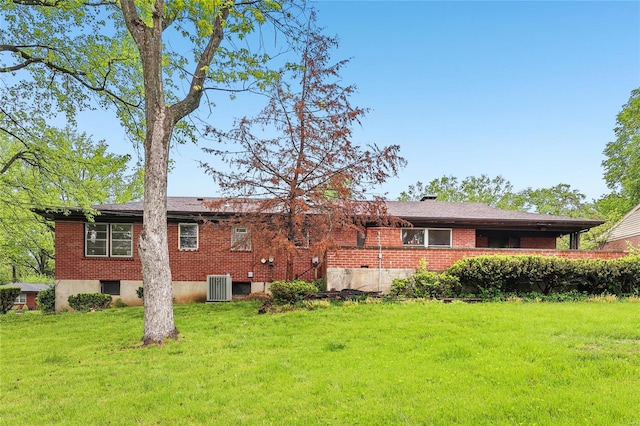 rear view of property with a yard, central air condition unit, and brick siding