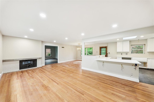 unfurnished living room with recessed lighting, a fireplace, baseboards, and a notable chandelier