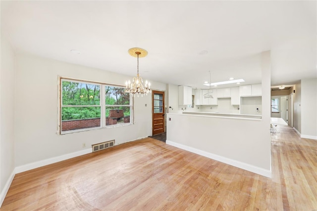 kitchen with visible vents, a chandelier, white cabinetry, baseboards, and light wood-style floors
