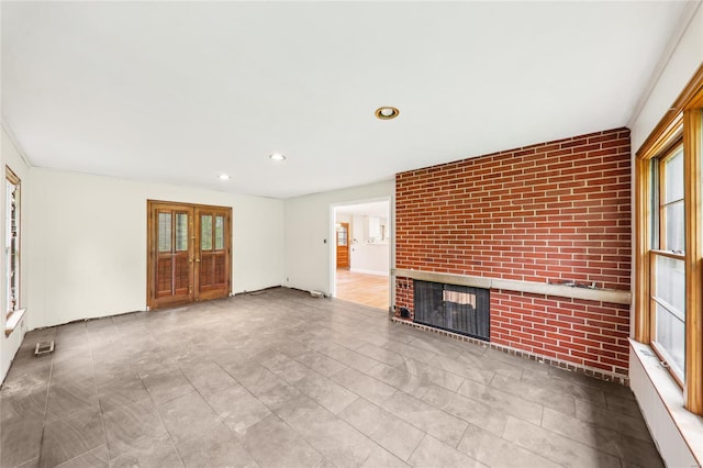 unfurnished living room with visible vents, french doors, a brick fireplace, and recessed lighting