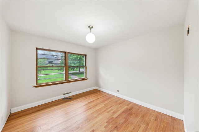 unfurnished room featuring baseboards, visible vents, and light wood-style floors