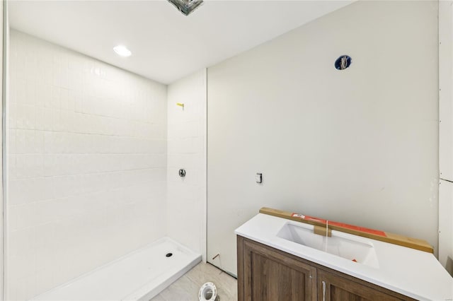 bathroom featuring a tile shower and a sink
