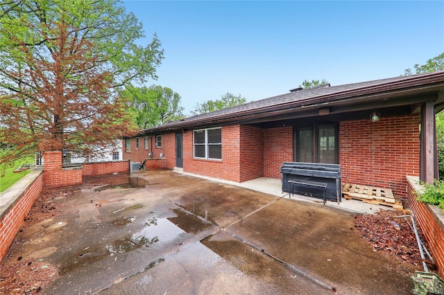 back of property featuring a patio and brick siding