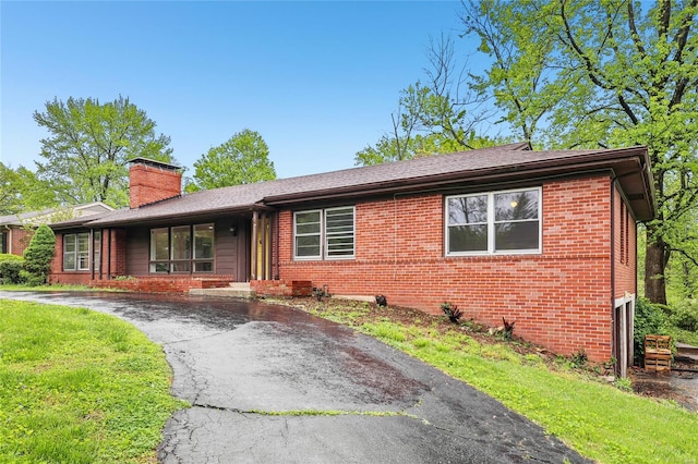 ranch-style house with brick siding, driveway, a chimney, and a garage
