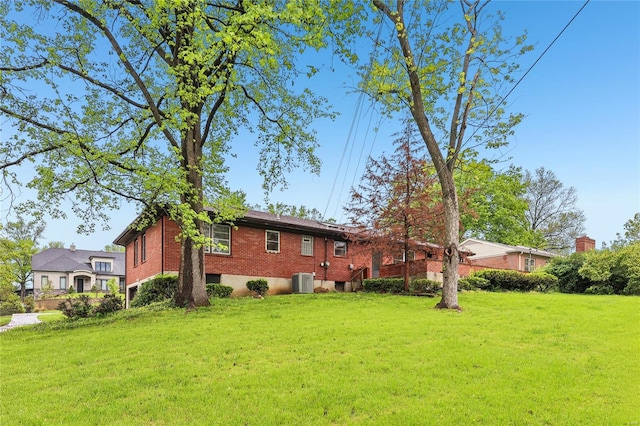 rear view of house with brick siding, a lawn, and central AC