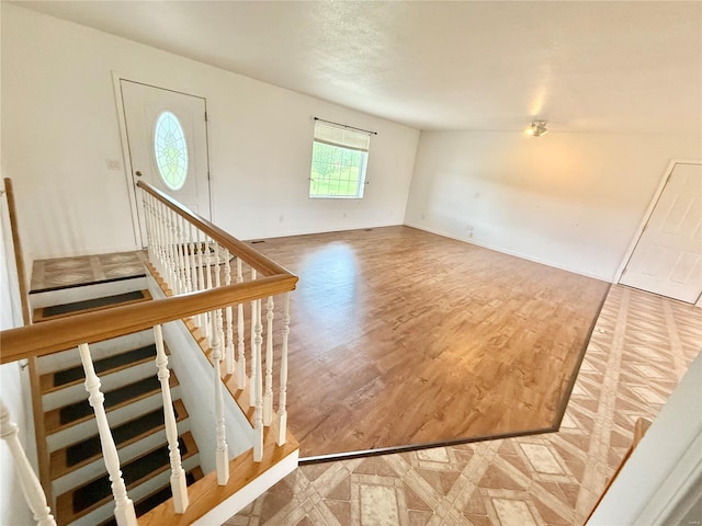 entryway featuring baseboards, wood finished floors, and stairway
