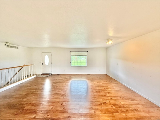 unfurnished room featuring baseboards, wood finished floors, and visible vents
