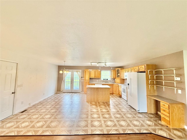 kitchen featuring light brown cabinets, light countertops, a textured ceiling, white fridge with ice dispenser, and a center island