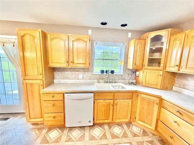 kitchen featuring a sink, dishwasher, light brown cabinets, and light countertops