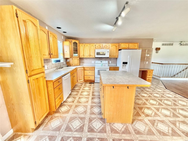 kitchen with a sink, white appliances, light countertops, a center island, and visible vents