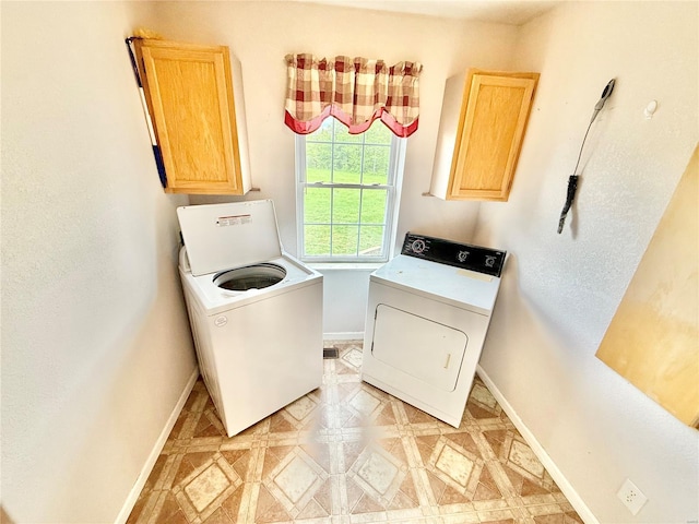 clothes washing area with separate washer and dryer, cabinet space, and baseboards