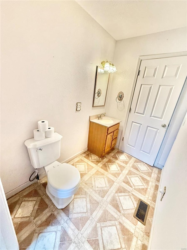 bathroom with vanity, baseboards, toilet, and visible vents