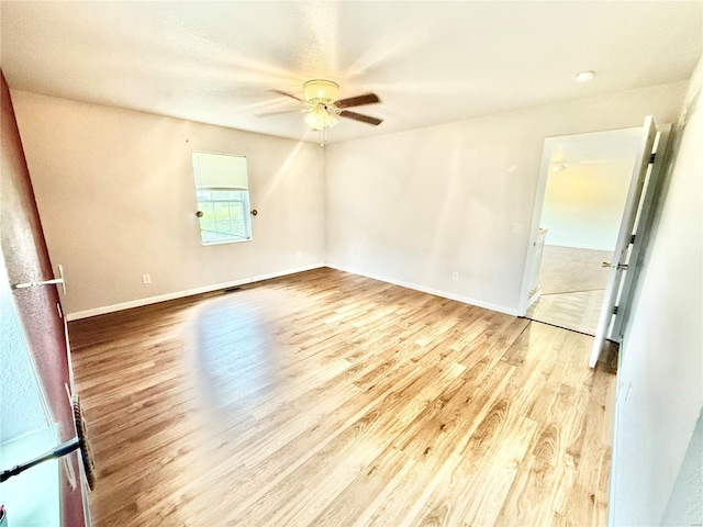 spare room with baseboards, a ceiling fan, and light wood-type flooring