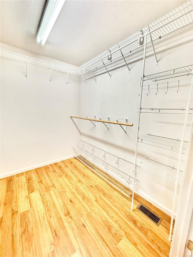 walk in closet with visible vents and wood finished floors